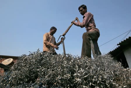 Workers flatten metal scrap on a supply truck at an industrial area in Mumbai