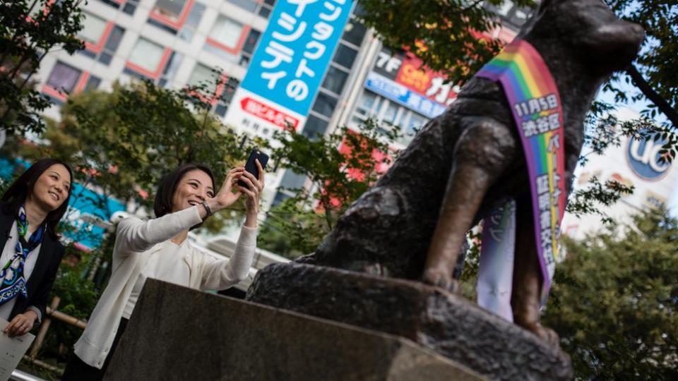 Una coppia gay scatta una foto alla statua di Hachiko