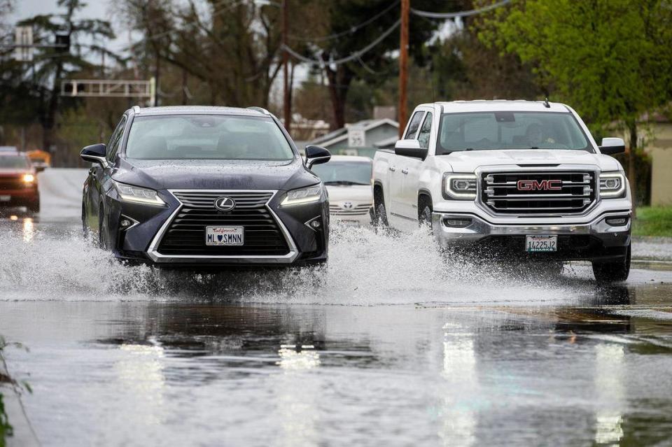 Motorists navigate a flooded section of R Street near the intersection with West 22nd Street in Merced, Calif., on Tuesday, March 14, 2023.