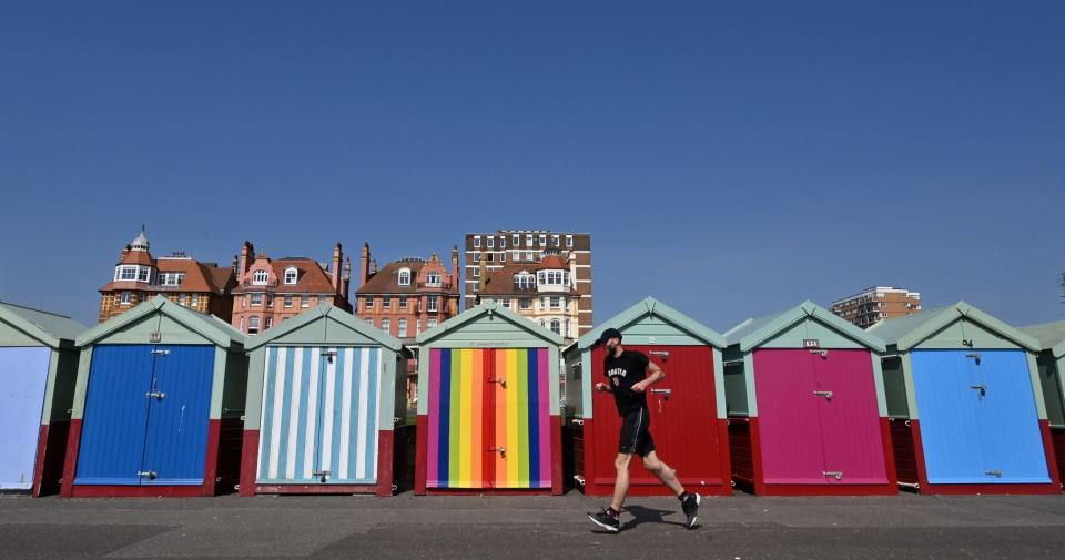 A man runs past beach huts along the seafront in Brighton, on the south coast of England on April 10 2020 - GLYN KIRK/AFP via Getty Images