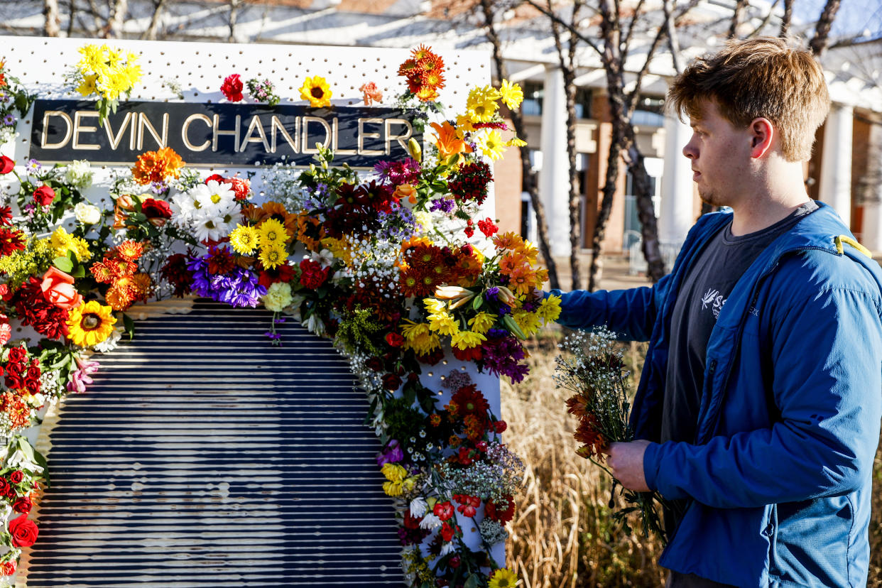 Ross Brown places flowers on a memorial for three slain University of Virginia football players on Saturday, Nov. 19, 2022, at John Paul Jones Arena on the university's campus in Charlottesville, Va. On Sunday, Nov. 13, University of Virginia football players Devin Chandler, Lavel Davis Jr. and D'Sean Perry were shot and killed by a teammate following a school field trip to Washington. (Shaban Athuman/Richmond Times-Dispatch via AP)