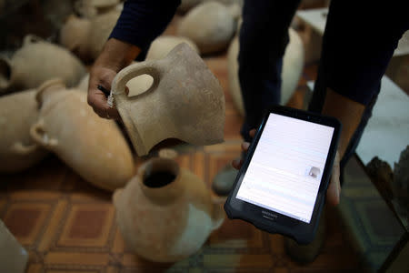 Eitan Klein, deputy director of the Israel Antiquities Authority's robbery prevention unit, holds part of a jug as he checks items at a shop selling antiques at a market in Jerusalem's Old City November 25, 2018. REUTERS/Corinna Kern