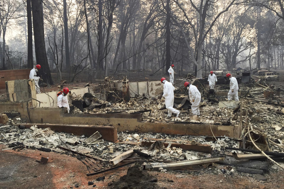 FILE - In this Nov. 15, 2018 file photo, volunteer rescue workers search for human remains in the rubble of homes burned in the Camp Fire in Paradise, Calif. Northern California officials have struggled to get a handle on the number of missing from the deadliest wildfire in at least a century in the United States. Authorities continue to log hundreds of reports by people who couldn't reach loved ones in the aftermath of the Camp Fire in Butte County. (AP Photo/Terry Chea, File)