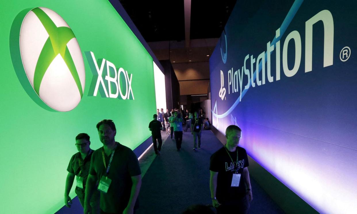 <span>Attendees walk past a Microsoft Xbox sign opposite a Sony PlayStation sign at E3 in 2015.</span><span>Photograph: Lucy Nicholson/Reuters</span>