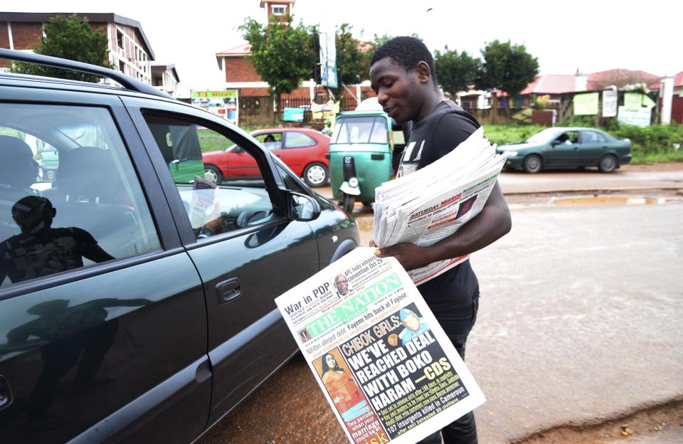 A newspaper vendor stands along road as he holds newspapers with a front page headline reading 'Chibok girls: We've reached deal with Boko Haram', in Abuja October 18, 2014. Nigeria said on Friday it had agreed a ceasefire with Islamist militants Boko Haram and reached a deal for the release of more than 200 schoolgirls kidnapped by the group six months ago. There was no immediate confirmation from the rebels, who have wreaked five years of havoc in Africa's top oil producer and triggered an international outcry by seizing the girls from the northeast town of Chibok in April. REUTERS/Stringer (NIGERIA - Tags: POLITICS RELIGION SOCIETY CRIME LAW)