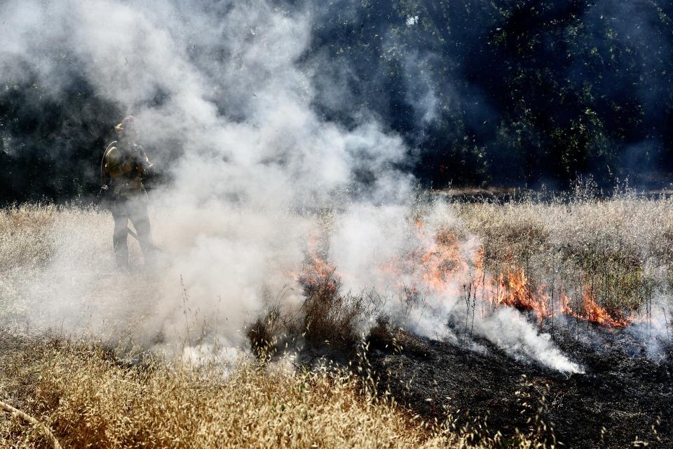 A Redding firefighter gets ready to spray water on a fire that started during a controlled fireworks demonstration behind Fire Station No. 8 off Churn Creek Road. Fire officials reminds residents that all fireworks are illegal in Shasta County without a permit.