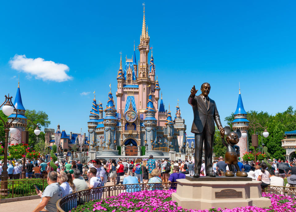 Castle in Walt Disney World and statue of Walt Disney and Mickey Mouse