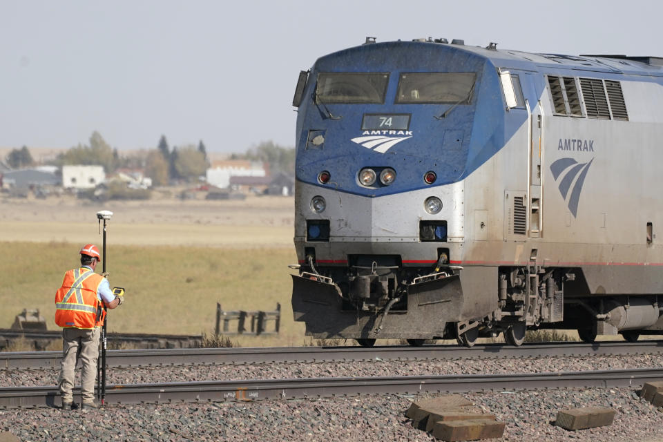 A person uses survey equipment, Sunday, Sept. 26, 2021, near an Amtrak train that derailed Saturday just west of Joplin, Mont. The westbound Empire Builder was en route to Seattle from Chicago, with two locomotives and 10 cars. (AP Photo/Ted S. Warren)