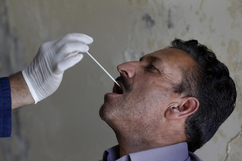 FILE - In this June 15, 2020, file photo, a health worker takes a nasal swab sample of a person during a door-to-door testing and screening facility for the new coronavirus, in Islamabad, Pakistan. Pakistan ranks among countries hardest hit by the coronavirus with infections soaring beyond 18,000, while the government, which has opened up the country hoping to salvage a near collapsed economy, warns a stunning 1.2 million Pakistanis could be infected by the end of August. (AP Photo/Anjum Naveed, File)