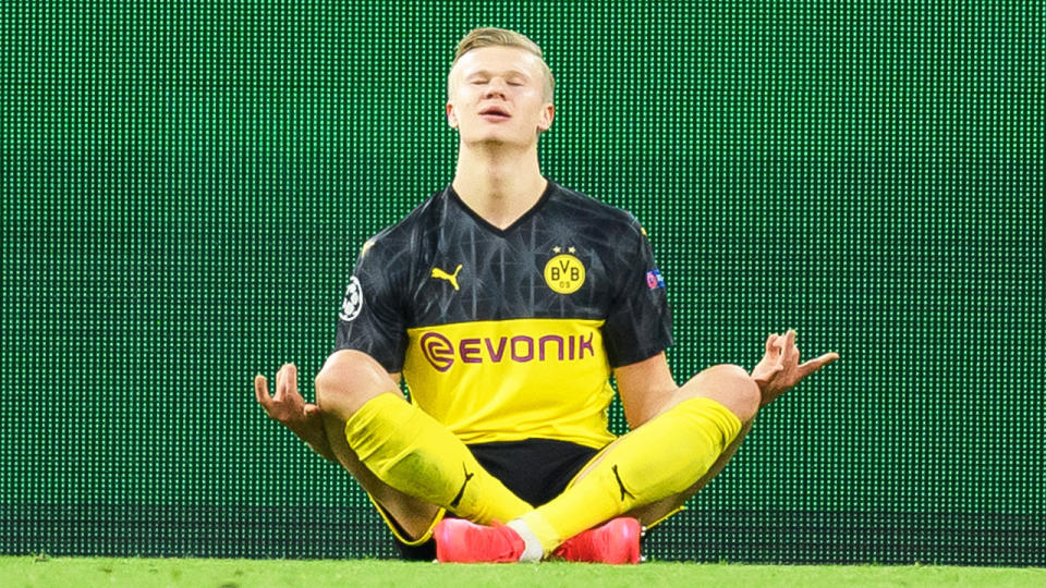 Erling Haaland sits down and celebrates after scoring a goal against PSG.