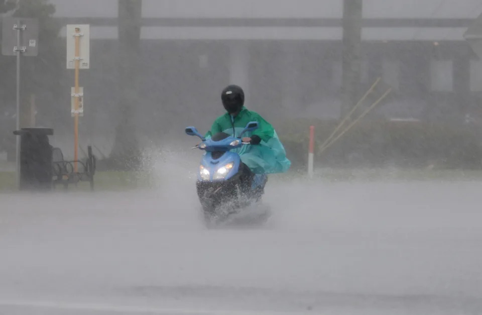 April 12, 2023: A person drives a scooter through a flooded street in Dania Beach, Florida. Heavy rain passed through the South Florida area causing some area flooding.