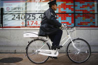A police officer rides a bicycle past an electronic stock board showing Japan's Nikkei 225 index at a securities firm in Tokyo Tuesday, Jan. 14, 2020. Asian shares followed Wall Street higher on Tuesday amid optimism that a trade deal between the U.S. and China will be a boon for the regional economy. (AP Photo/Eugene Hoshiko)
