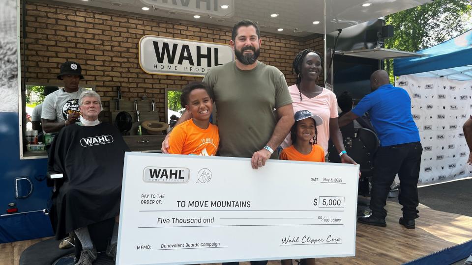 Ryan Boyette and his wife,  Jazira Awad, receive a $5,000 donation for their nonprofit from Wahl Grooming on Saturday, May 6, 2023, at the Sevier Park Fest in Nashville. The charity, To Move Mountains, provides education for children in a remote area of Sudan in Africa