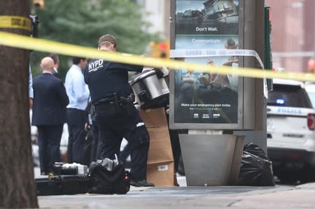 A NYPD officer is seen collecting evidences near West 16th Street and Seventh Avenue as police were investigating suspicious packages in Manhattan