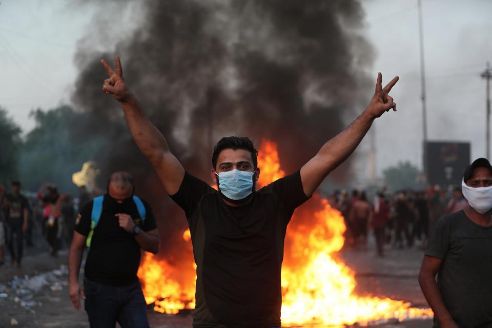 An anti-government protester flashes the victory sign during a demonstration in Baghdad, Iraq, Thursday, Oct. 3, 2019. Iraqi security forces fired live bullets into the air and used tear gas against a few hundred protesters in central Baghdad on Thursday, hours after a curfew was announced in the Iraqi capital on the heels of two days of deadly violence that gripped the country amid anti-government protests that killed over 19 people in two days. (AP Photo/Hadi Mizban)