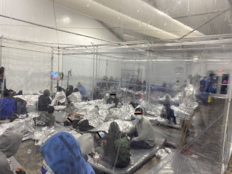 Migrants crowd a room with walls of plastic sheeting at the U.S. Customs and Border Protection temporary processing center in Donna