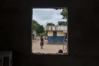 A boy looks into a church as a woman walks home during Christmas mass in the village of Kimbanza, in Moanda, Democratic Republic of the Congo, Monday, Dec. 25, 2023. (AP Photo/Mosa'ab Elshamy)