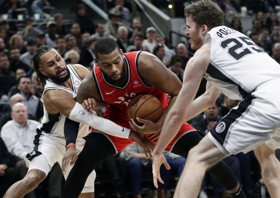 Toronto Raptors center Greg Monroe, center, is pressured by San Antonio Spurs guard Patty Mills, left, and center Jakob Poeltl (25) during the first half of an NBA basketball game, Thursday, Jan. 3, 2019, in San Antonio. (AP Photo/Eric Gay)
