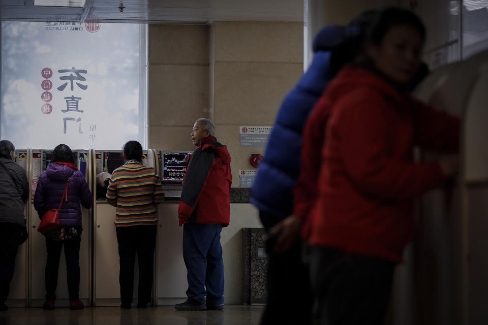 Chinese investors monitor stock prices at a brokerage house in Beijing, Friday, Dec. 20, 2019. Stocks were mixed in early trading in Asia on Friday after Wall Street posted more record highs, extending the market's gains for the week. (AP Photo/Andy Wong)