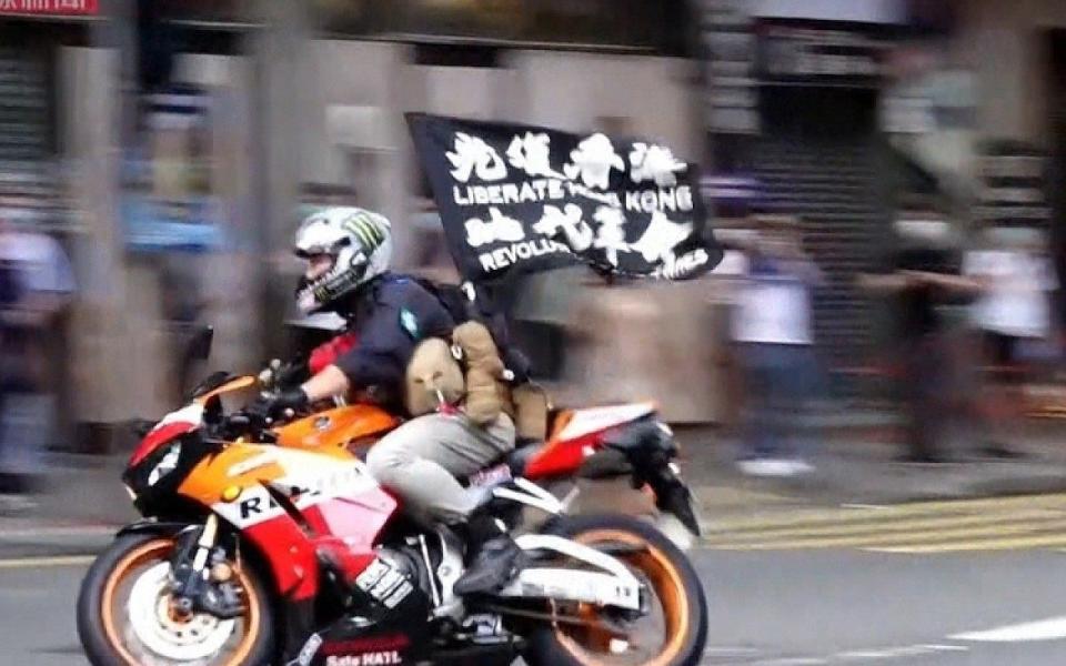 Tong Ying-kit on a motorbike with a protest flag on July 1, 2020 shortly before crashing into police during a demonstration