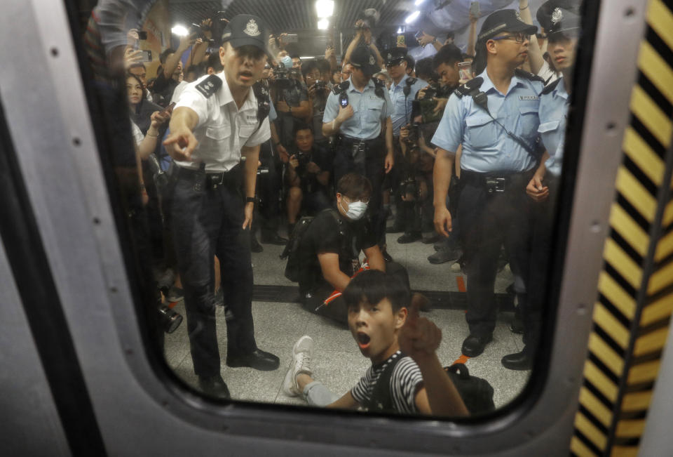 Two protesters are surrounded by police officers while sitting on the floor saying he is injured at a subway platform in Hong Kong Wednesday, July 24, 2019. Subway train service was disrupted during morning rush hour after dozens of protesters staged what they called a disobedience movement to protest over a Sunday mob attack at a subway station. (AP Photo/Vincent Yu)