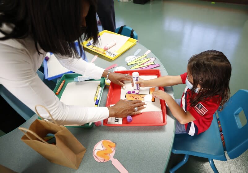 HARBOR CITY, CA - AUGUST 16: Normont Early Education Center teacher Vernida Watson helps student Lazarus Alvarado as School on the first day of in class instruction on August 16, as LAUSD officials welcome students, teachers, principals, at various school sites across Los Angeles. For the younger students it will be their first time in a classroom. Normont Elementary on Monday, Aug. 16, 2021 in Harbor City, CA. (Al Seib / Los Angeles Times).