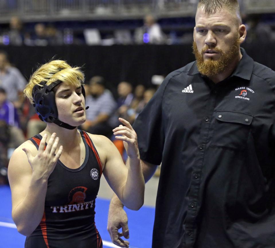 Mack Beggs, left, a transgender wrestler from Euless Trinity High School, stands with his coach Travis Clark during a quarterfinal match against Mya Engert, of Amarillo Tascosa, during the State Wrestling Tournament, Friday, Feb. 24, 2017, in Cypress, Texas. Beggs was born a girl and is transitioning to male but wrestles in the girls division. ( Melissa Phillip/Houston Chronicle via AP)