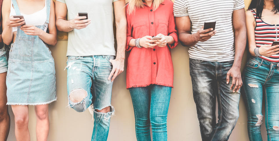 Group of millennial friends watching smart mobile phones - Teenagers addiction to new technology trends - Concept of youth, tech, social and friendship - Focus on smartphones