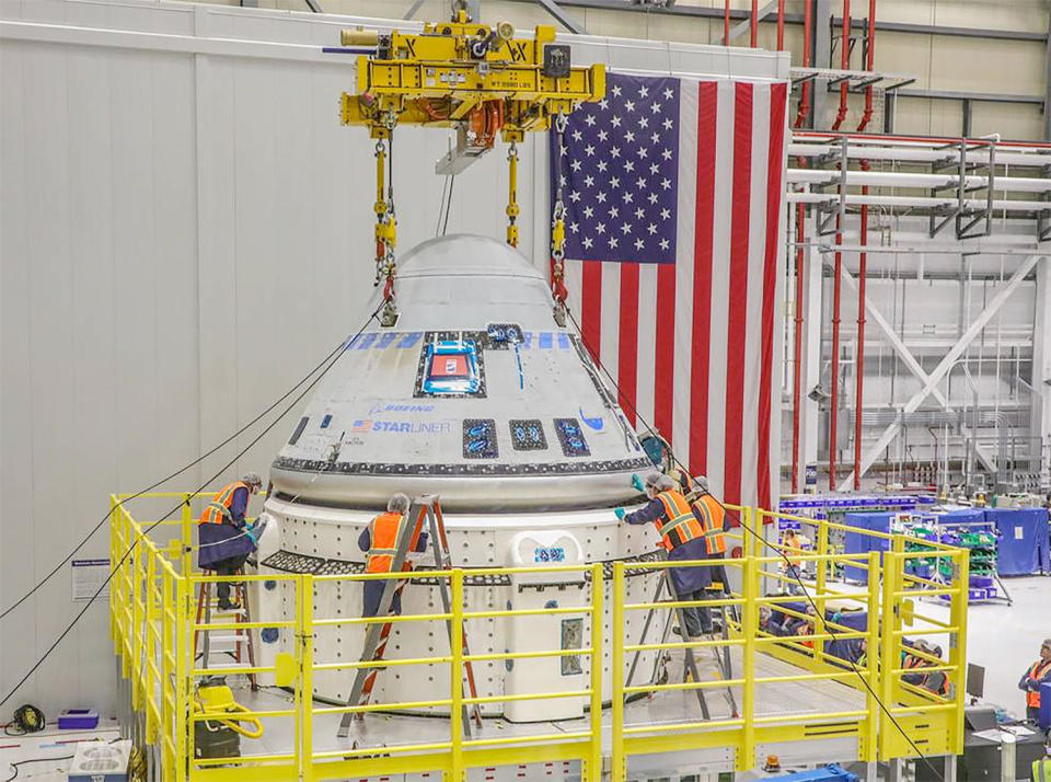 Boeing engineers attach a Starliner crew capsule to its propulsion and service module in preparation for the company's first piloted test flight of the astronaut ferry ship. That flight, carrying two NASA astronauts, is now targeted for launch no earlier than July 21. / Credit: Boeing