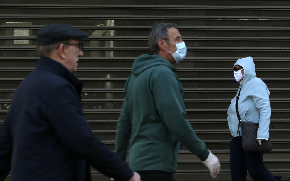 People wearing a mask against the spread of the new coronavirus walk during a curfew in downtown Belgrade, Serbia, Tuesday, April 21, 2020. Serbia's elderly on Tuesday ventured outside their homes for the first time in more than a month as the authorities eased some of the strict measures that have been in place against the new coronavirus. Serbia has introduced some of the toughest rules in Europe as part of efforts to curb the spread of the virus. (AP Photo/Darko Vojinovic)