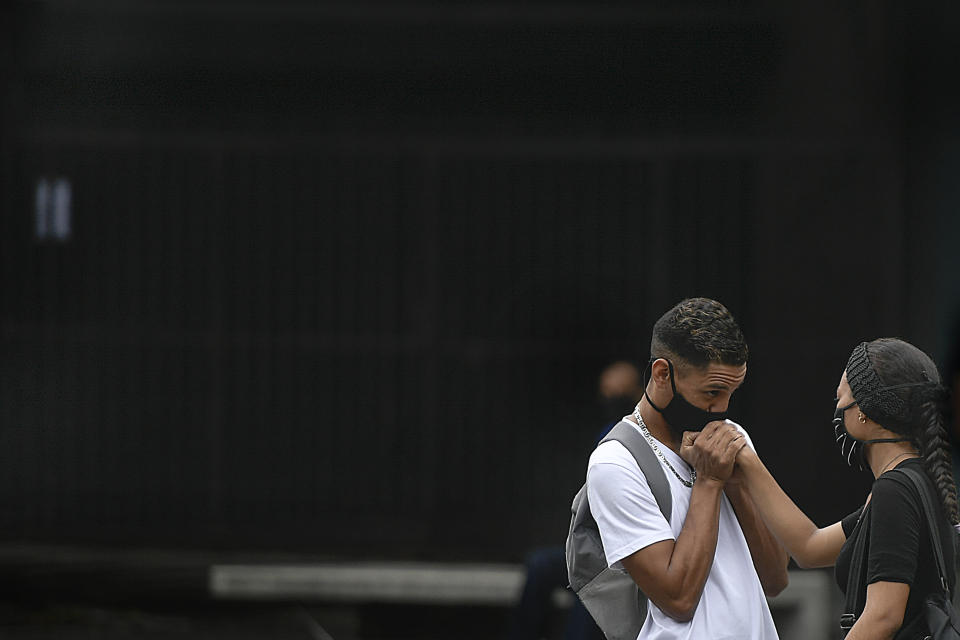 A man, wearing a protective face mask, kisses his girlfriend's hand on Sabana Grande boulevard in Caracas, Venezuela, Saturday, Aug. 1, 2020, amid the new coronavirus pandemic. (AP Photo/Matias Delacroix)