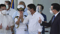 In this photo provided by the Presidential Communications Operations Office-Office of the Global Media Public Affairs, Philippine President Rodrigo Duterte, center, holds a vial containing the Sinovac vaccine from China as it arrives at the Villamor Air Base in Manila, Philippines on Sunday Feb. 28, 2021. The Philippines is due to receive its first batch of COVID-19 vaccine Sunday, among the last in Southeast Asia to secure the critical doses despite having the second-highest number of coronavirus infections and deaths in the hard-hit region. (PCOO-OGMPA via AP)