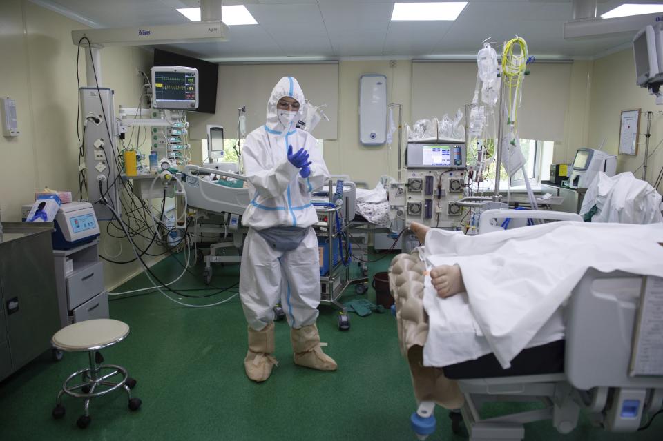 FILE - In this Tuesday, July 13, 2021 file photo, a medic wearing a special suit to protect against coronavirus prepares to treat a patient with coronavirus at the City hospital No. 52 for coronavirus patients in Moscow, Russia. A new report from Russia's state statistics agency on Saturday, Aug. 28 shows the country recorded a record number of deaths in July of people infected with coronavirus. The report from the Rosstat agency said 50,421 people suffering from COVID-19 died during the month, sharply higher than the previous record of 44,435 in December. (AP Photo/Denis Kaminev)