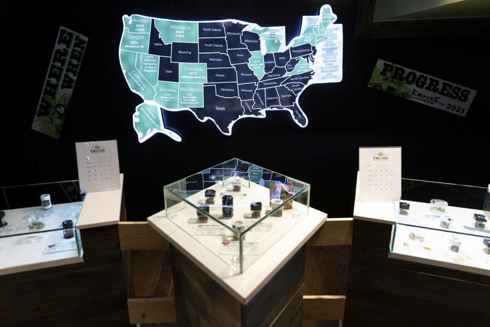 A map of cannabis legalization in the U.S. glows behind flower displays at the Empire Cannabis Club, Wednesday, Nov. 16, 2022, in New York. Under pressure to launch one of the nation’s most hotly anticipated legal marijuana markets, the state Cannabis Control Board is set Monday to consider awarding some dispensary licenses to entrepreneurs and nonprofit groups — a major step that comes as cannabis regulators stress that they're trying to stop unlicensed sellers. (AP Photo/Julia Nikhinson)