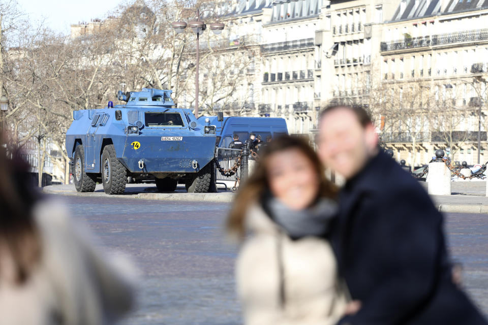 People pose in front of a police armored vehicle near at the Arc de Triomphe, Saturday, Feb.12, 2022 in Paris. Protesters angry over pandemic restrictions are driving toward Paris to blockade the French capital despite a police ban. The protesters organized online, galvanized in part by truckers who have blockaded Canada's capital. Paris region authorities deployed more than 7,000 police officers to tollbooths and other key sites to try to prevent a blockade. (AP Photo/Adrienne Surprenant)