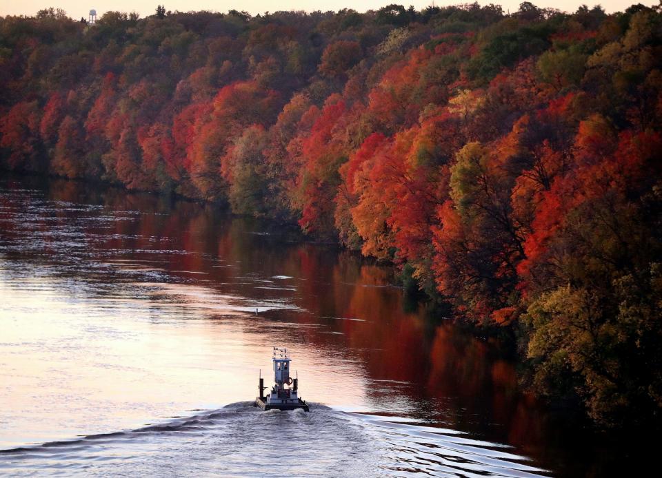 The fall colors along the Mississippi River are near peak as a small tug boat heads up river, seen from the Franklin Avenue Bridge, Tuesday, Oct. 17, 2017, Minneapolis. The babies found in 1999 and 2003 were found around 50 miles southeast of the bridge.