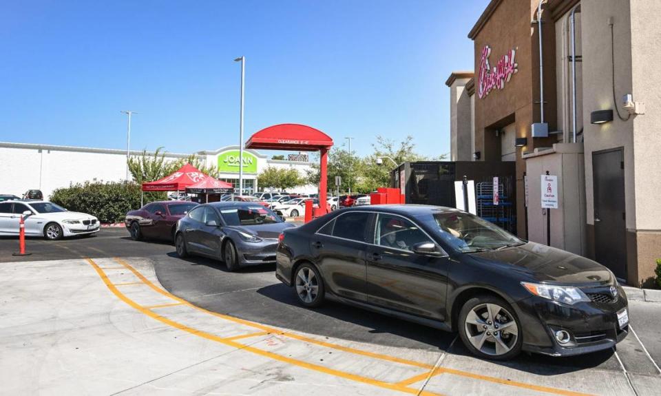 Cars wait in the drive-thru lane at Chick-fil-A’s River Park location at Blackstone and Nees in Fresno on Monday, Aug. 7, 2023. The newly added second lane is blocked by an orange post as cars file into one lane to get their food.