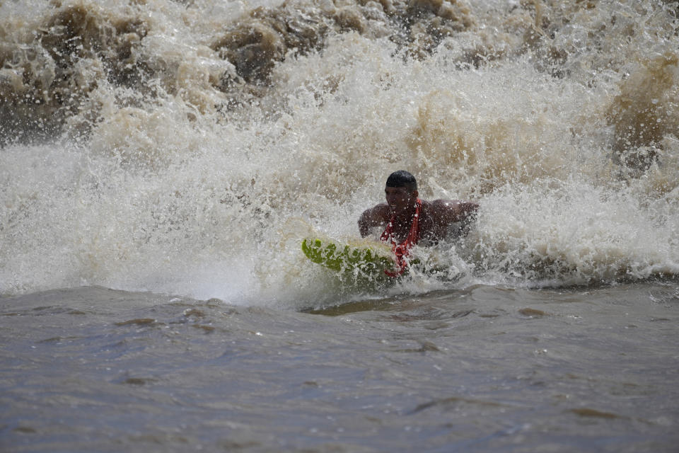 Brazilian surfer Naysson Costa prepares to ride the tidal bore wave known as "Pororoca," during the Amazon Surf Festival held in the Canal do Perigoso, or "Dangerous Channel," at the mouth of the Amazon River near Chaves, Marajo Island archipelago, Para state, Brazil, Monday, June 5, 2023. The Pororoca, a word from an Amazonian Indigenous dialect that means "destroyer" or "great blast," happens twice a day when the incoming ocean tide reverses the river flow for a time. (AP Photo/Eraldo Peres)