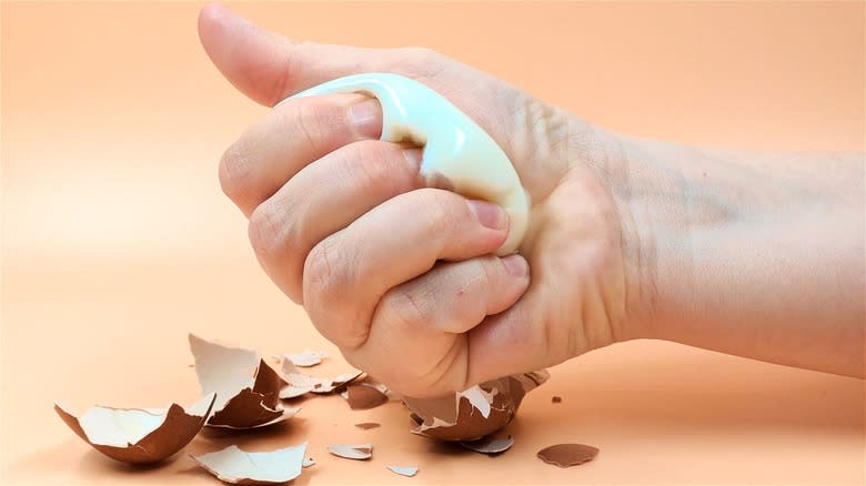 Hand crushing hard-boiled egg 