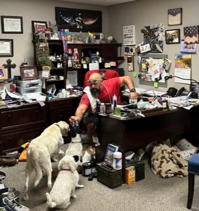 Dan Marcon, owner of Marc-On Shooting in Chippewa Falls, in the office of his gun shop with his dogs. Marcon credits his dogs for pulling him back from suicide.