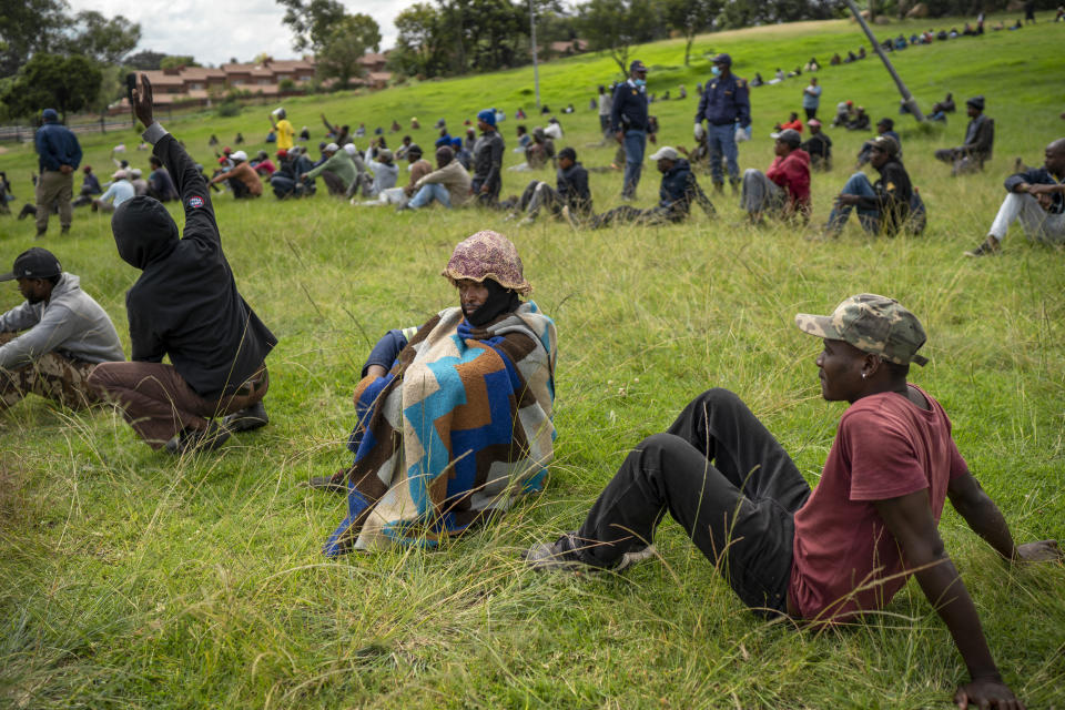 Homeless recyclers and other destitute people, some of whom said they have not eaten in three days practice social distancing as they lineup in a Johannesburg park, waiting to receive food baskets from private donors, Thursday, April 9, 2020. Because of South Africa's imposed lockdown to contain the spread of COVID-19, many people who don't have savings and are unable to work are not able to buy food. (AP Photo/Jerome Delay)