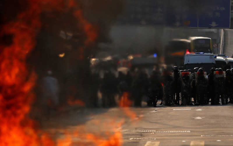 Police officers stand next to a burning barricade during an anti-government protest in Hong Kong China