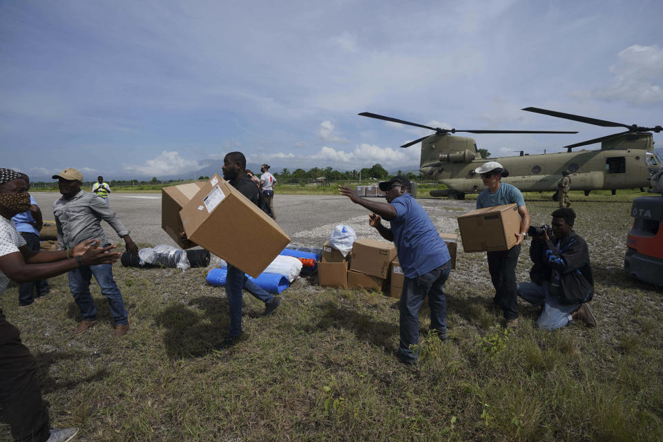 Residents help Team Rubicon's disaster response team unload aid at the airport from a U.S. Army helicopter to take to the hospital where the team is treating residents injured in the 7.2 magnitude earthquake in Les Cayes, Haiti, Thursday, Aug. 19, 2021. (AP Photo/Fernando Llano)