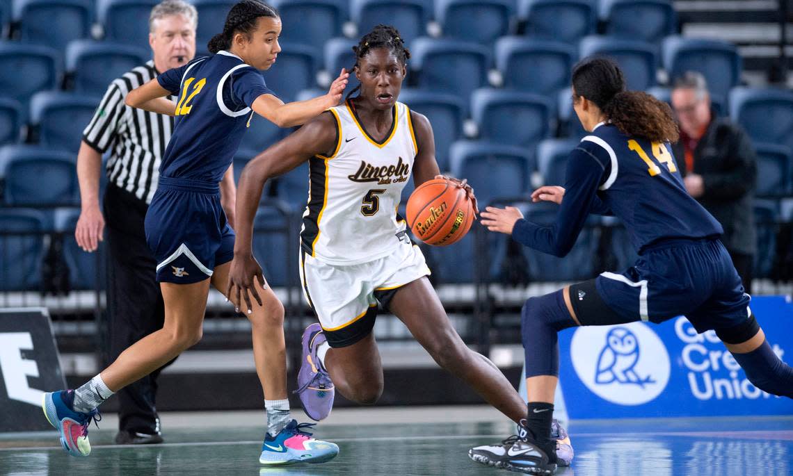 Lincoln’s Oliviyah Edwards pushes the ball up court between Everett defenders Alana Washington (left) and Mae Washington during their opening-round game at the WIAA state basketball tournament in the Tacoma Dome in Tacoma, Washington, on Wednesday, March 1, 2023. Lincoln won the game, 45-43.