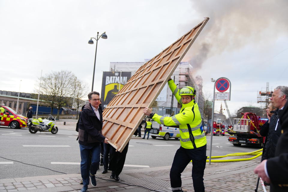 Former Danish Minister of Culture and current CEO of Danish Business, Brian Mikkelsen, left, assists with the evacuation of paintings from the Boersen burning in Copenhagen on Tuesday, April 16, 2024. A fire raged through one of Copenhagen’s oldest buildings on Tuesday, causing the collapse of the iconic spire of the 17th-century Old Stock Exchange as passersby rushed to help emergency services save priceless paintings and other valuables. (Ida Marie Odgaard/Ritzau Scanpix via AP)