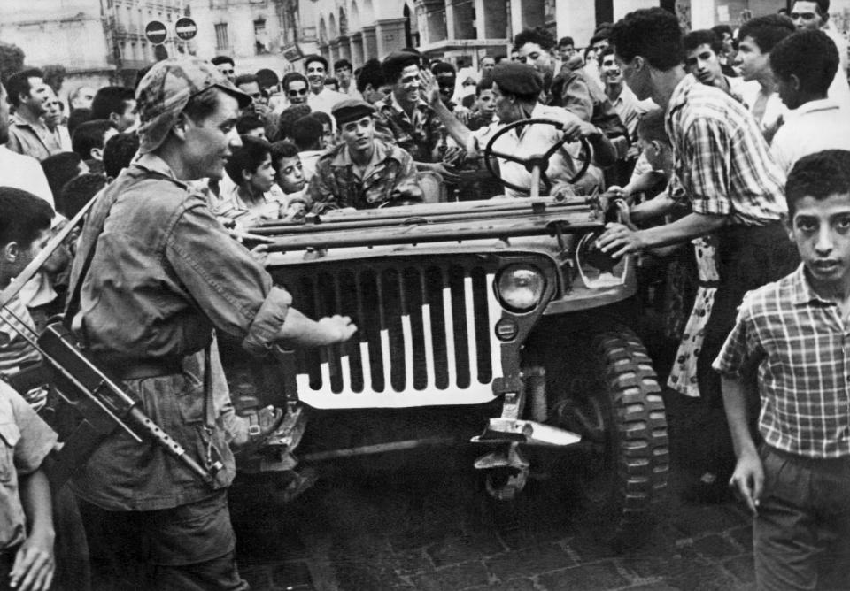 FILE - A jeep of the Algerian Liberation Front (FLN) is surrounded by an enthusiastic crowd in Algiers, Algeria, in July 1962. Algeria is celebrating 60 years of independence from France on Tuesday July 5, 2022 with nationwide ceremonies, a pardon of 14,000 prisoners and its first military parade in years. Tuesday's events mark 60 years since the official declaration of independence on July 5, 1962, after a brutal seven-year war which ended 132 years of colonial rule. The war, which killed at least 1.5 million people, remains a point of tension in relations between Algeria and France. (AP Photo, File)