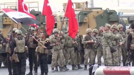 Iraqi and Turkish soldiers wave flags at the Habur Border Gate between Turkey and Iraq in this still image taken from video, October 31, 2017. IHA/ via REUTERS