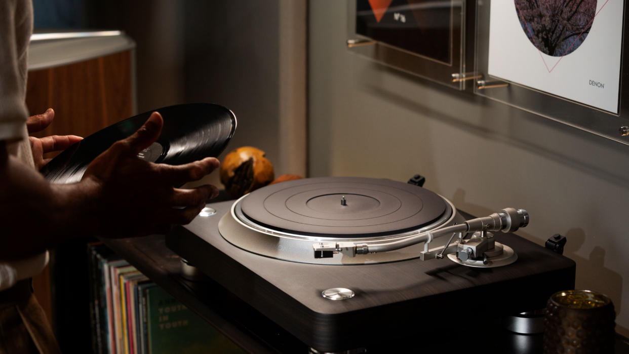  Denon DP-3000NE lifestyle image featuring a man placing a record on a turntable. 