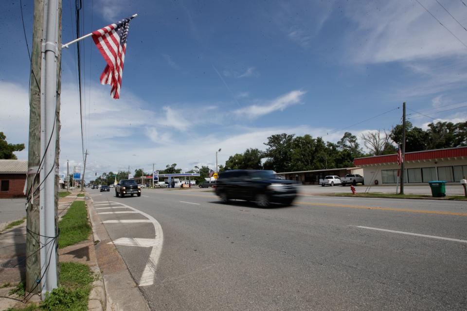 Cars pass by as American flags that line the highway in Blountstown, Florida fly in the wind Wednesday, July 21, 2021.