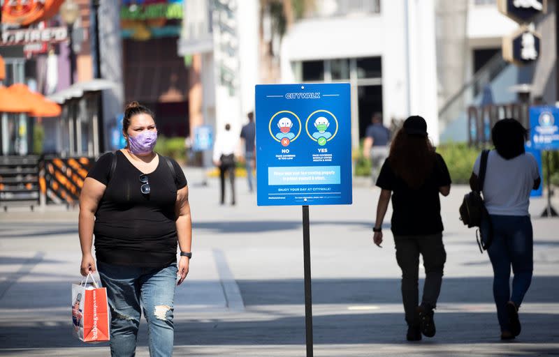 A person wearing a face mask walks through Universal CityWalk Hollywood during the outbreak of the coronavirus disease (COVID-19), in Universal City